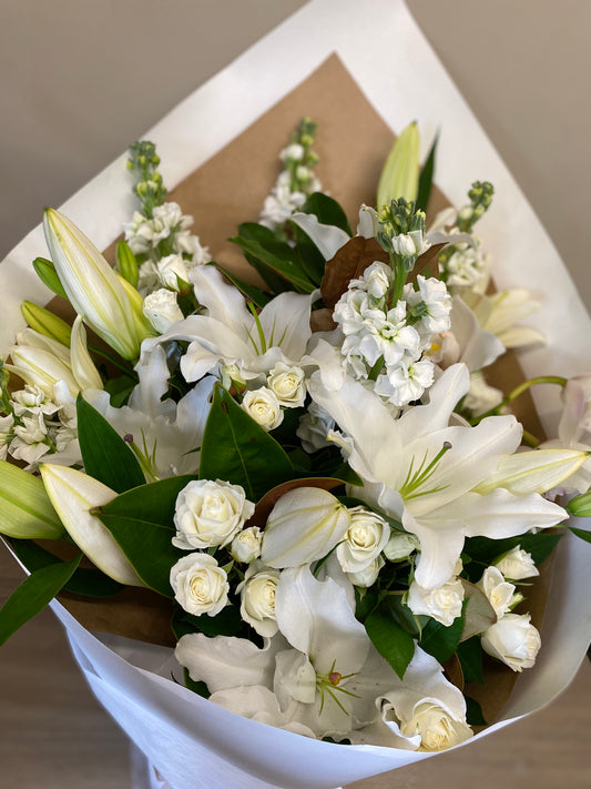 Simply elegant bouquet of white flowers including lilies and roses, with foliage